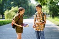 Portrait of students in a city park, teenage schoolchildren a boy and a girl are standing on the path and discussing lessons,
