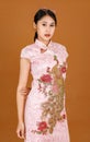 Portrait studio shot of millennial Asian female model in pink cheongsam qipao traditional festival peacock and flowers pattern Royalty Free Stock Photo