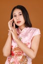 Portrait closeup studio shot millennial Asian female model in pink Chinese cheongsam qipao traditional peacock & flowers pattern
