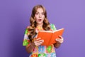 Portrait of stunned astonished pretty girl dressed print t-shirt read interesting book open mouth isolated on violet Royalty Free Stock Photo