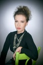 Portrait of a stunning fashionable model sitting in a green chair, studio shot. Close up portrait of young beautiful woman Royalty Free Stock Photo