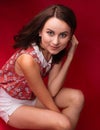 Portrait of a stunning sexy young brunette girl on a red background, a floral print blouse and white short shorts. Beauty