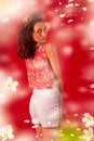 Portrait of a stunning sexy young brunette girl on a red background, a floral print blouse and white short shorts. Beauty