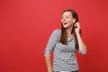 Portrait of stunning young girl in casual striped clothes with wireless earphones listening music isolated on bright red Royalty Free Stock Photo