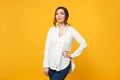 Portrait of stunning young woman in white shirt, jeans standing and looking camera isolated on yellow orange wall Royalty Free Stock Photo