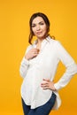 Portrait of stunning young woman in white shirt, jeans standing and looking camera isolated on yellow orange wall Royalty Free Stock Photo