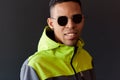 Portrait of stylish attractive African American man smiling and looking through sunglasses, wearing green sport hoody, posing on Royalty Free Stock Photo