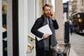 Portrait of a stylish bearded business man with a laptop in his hands talking on the smartphone Royalty Free Stock Photo