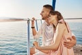 Portrait of stylish couple in love, hugging while sitting on bow of private yacht and enjoying view of sea. Husband took Royalty Free Stock Photo