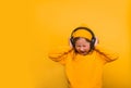 Portrait of stylish cute little kid girl listening music in headphones and singing against pink background. School child Royalty Free Stock Photo