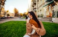 Portrait of a stylish dog-owner female hugging her little yorkshire terrier, wearing a fashionable hoodie, sitting on the green Royalty Free Stock Photo