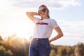 Portrait of stylish female youngster in casual clothes and shades, enjoys summer time, poses against clear sky, has trendy hairsty