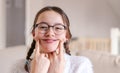 Portrait of stylish foolish attractive smiling preteen girl in glasses with pigtails making artificial smile by fingers on her ch