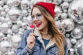 Portrait of stylish girl in denim jacket eating candy and looking away. Wonderful european lady in Royalty Free Stock Photo