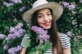 Portrait of stylish girl hipster on the street among a blossoming lilac