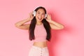 Portrait of stylish good-looking asian girl enjoying listening music in headphones, looking dreamy and upbeat with Royalty Free Stock Photo