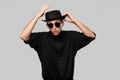 Portrait of a man in a black shirt, pork pie and sun glasses hat isolated over grey background. Royalty Free Stock Photo