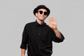 Portrait of a man in a black shirt, pork pie and sun glasses hat isolated over grey background. Royalty Free Stock Photo