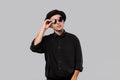 Portrait of a man in a black shirt, pork pie and sun glasses hat isolated over grey background. Royalty Free Stock Photo