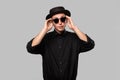 Portrait of a man in a black shirt, pork pie and sun glasses hat isolated over grey background. Royalty Free Stock Photo