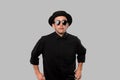 Portrait of a man in a black shirt, pork pie and sun glasses hat  over grey background. Royalty Free Stock Photo