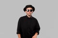 Portrait of a man in a black shirt, pork pie and sun glasses hat  over grey background. Royalty Free Stock Photo