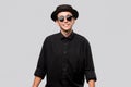 Portrait of a man in a black shirt, pork pie and sun glasses hat  over grey background. Royalty Free Stock Photo