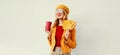 Portrait stylish happy smiling woman with yellow maple leaves, coffee cup in french beret posing over gray wall Royalty Free Stock Photo