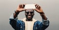 Portrait of stylish happy smiling young african american man taking selfie with phone on gray background Royalty Free Stock Photo