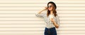 Portrait of stylish happy smiling young woman with cup of coffee looking away wearing black round hat, sunglasses, striped shirt Royalty Free Stock Photo