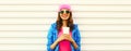 Portrait of stylish happy smiling young woman with cup of coffee wearing colorful pink hat, blue jacket on white background Royalty Free Stock Photo