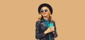 Portrait of stylish happy smiling young woman holds cup of coffee wearing round hat and rock style black leather jacket posing on Royalty Free Stock Photo