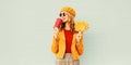 Portrait stylish happy woman drinking coffee with yellow maple leaves wearing french beret posing over gray wall Royalty Free Stock Photo