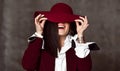 Portrait of stylish high-society lady in black jacket and white shirt pulling down hat brim hiding her eyes and laughs Royalty Free Stock Photo