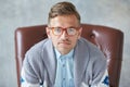 Portrait of a stylish intelligent man with glasses stares into the camera, good view, small unshaven, charismatic, blue shirt, gra Royalty Free Stock Photo