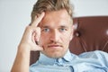 Portrait of a stylish intelligent man, small unshaven, charismatic, blue shirt, sitting on a brown leather chair, dialog