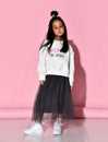 Portrait of a stylish Korean girl wearing a white sweater, tulle skirt, sneakers and red glasses.