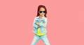 Portrait of stylish little girl child wearing sunglasses, jeans jacket on pink background Royalty Free Stock Photo