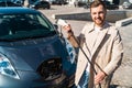 Portrait of stylish man with electric car charging connector in hands. Royalty Free Stock Photo