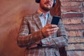 Portrait of a stylish man in a flannel suit and glasses listenin