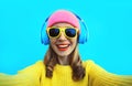 Portrait of stylish modern cool happy young woman taking selfie with mobile phone listening to music in wireless headphones Royalty Free Stock Photo