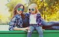 Portrait stylish mother and child wearing a sunglasses, shirts in a city park Royalty Free Stock Photo