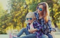 Portrait stylish mother and child wearing a sunglasses, shirts in a city park Royalty Free Stock Photo