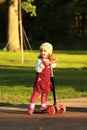 Portrait of a stylish one year old girl riding a scooter on a lovely sunlit summer day Royalty Free Stock Photo