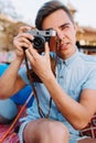 Portrait of stylish photographer in trendy light-blue denim shirt taking photo on blur background. Handsome young man