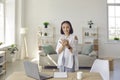 Portrait of stylish senior business woman standing with phone near workplace in her home office.