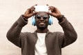 Portrait stylish smiling african man taking selfie picture by smartphone in wireless headphones listening to music Royalty Free Stock Photo