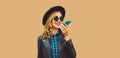 Portrait of stylish smiling young woman holding smartphone using voice command recorder, assistant or takes calling wearing black