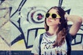 Portrait of a stylish teenage girl in sunglasses posing near graffiti wall Royalty Free Stock Photo