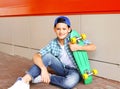 Portrait stylish teenager boy with skateboard in city